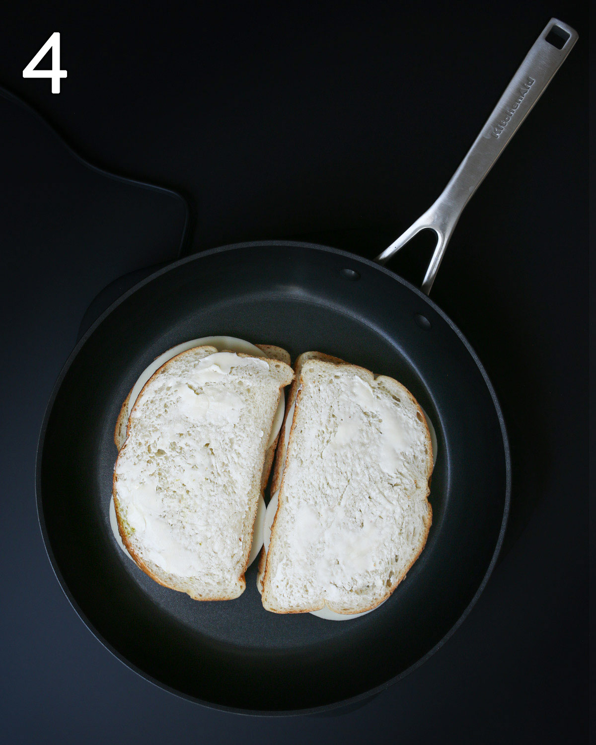 assembled sandwich in skillet with butter on the top side of the bread.