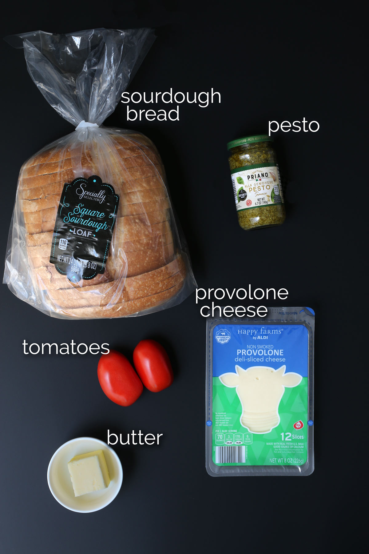 ingredients for pesto grilled cheese laid out on a black table.