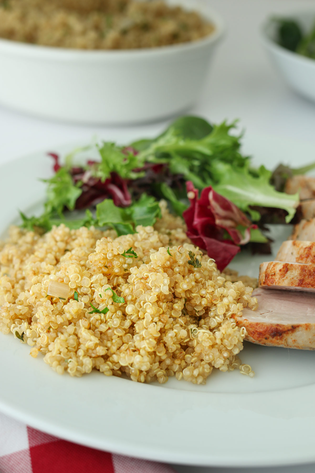 close up shot of quinoa pilaf on dinner plate with salad and pork tenderloin.