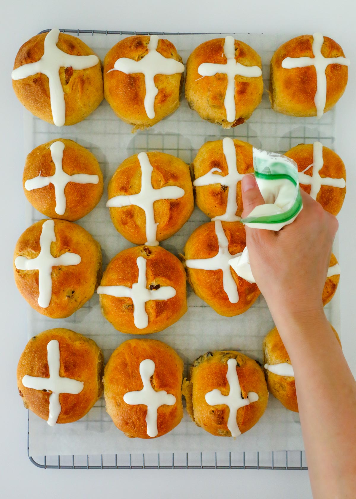 piping frosting onto the buns.