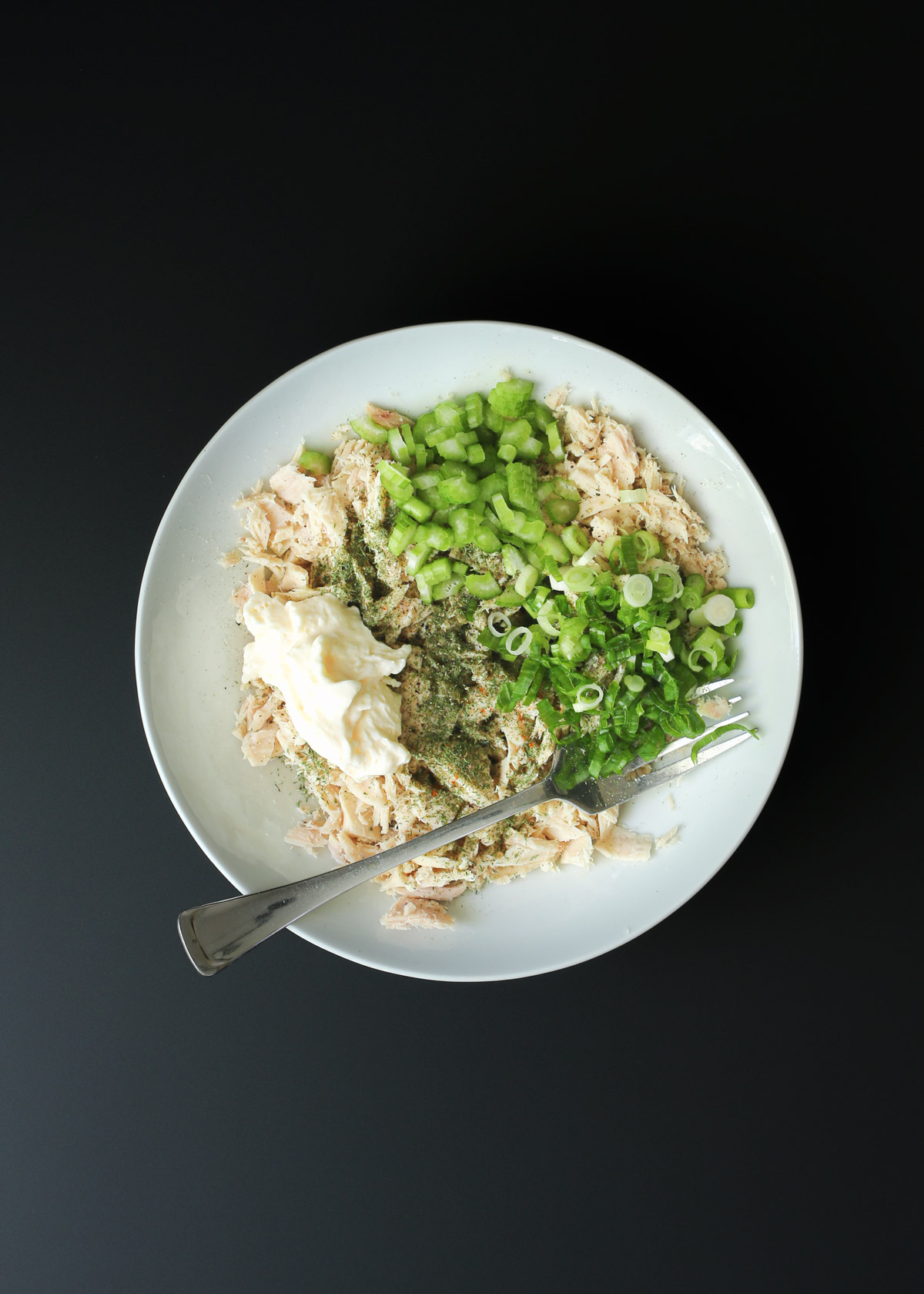 mayo, spices, celery, and onion added to bowl of tuna.