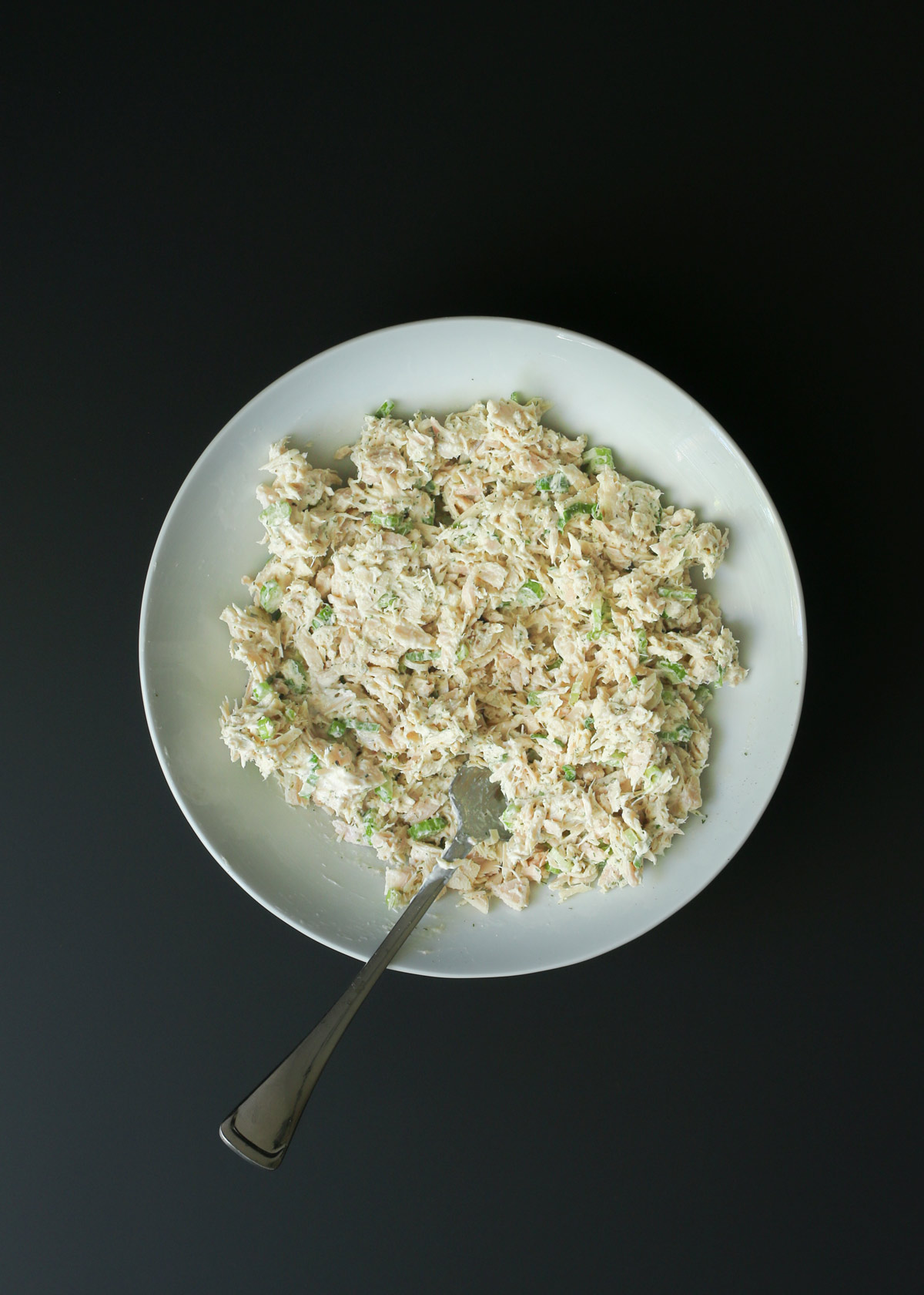combined tuna salad in white bowl with fork.