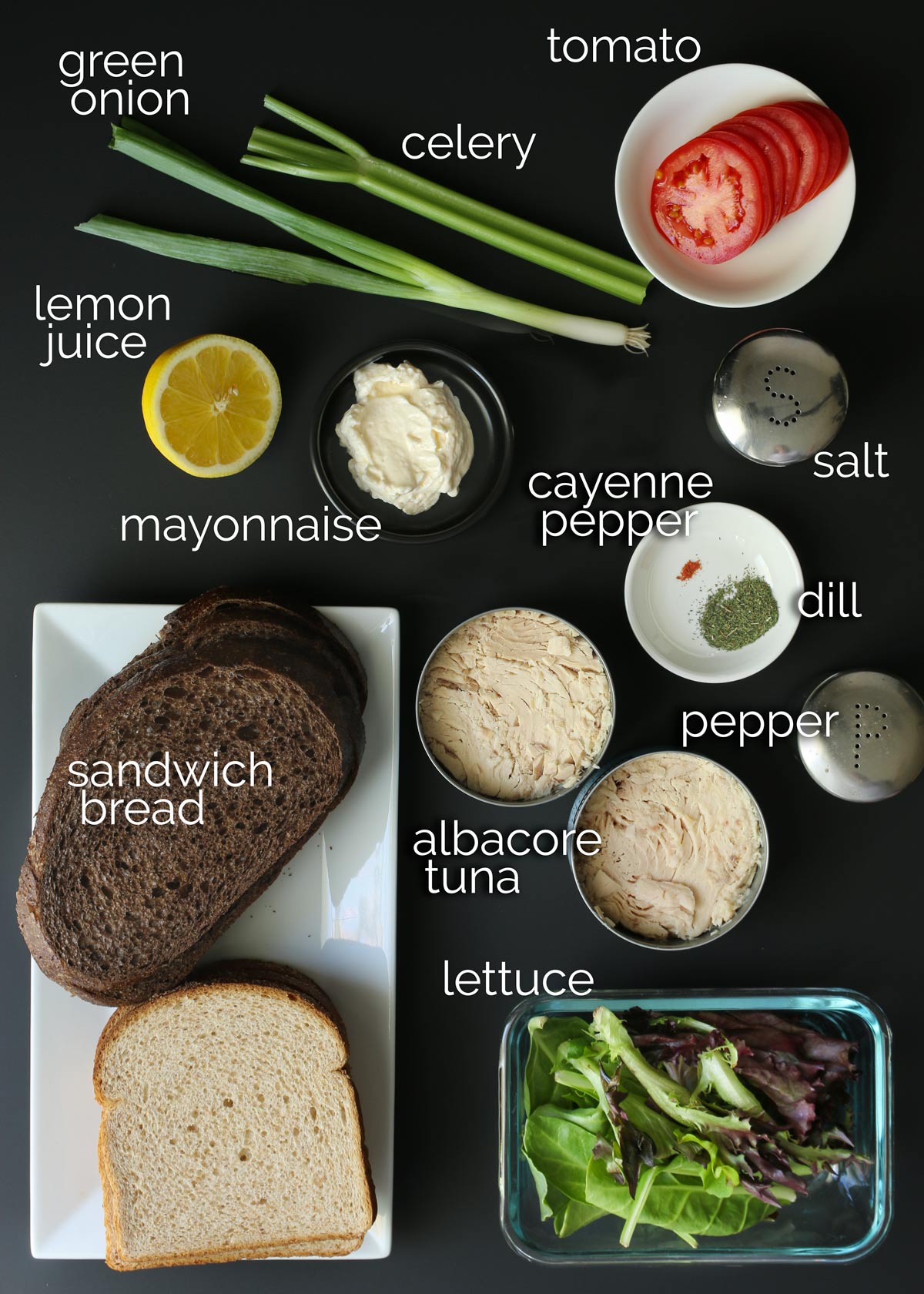 ingredients for tuna sandwich recipe laid out on black counter.