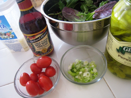 A bottle of vinegar and a bowl of Salad