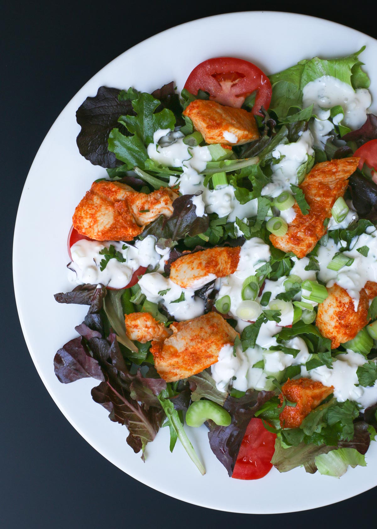 overhead shot of a large salad with buffalo chicken and blue cheese dressing.
