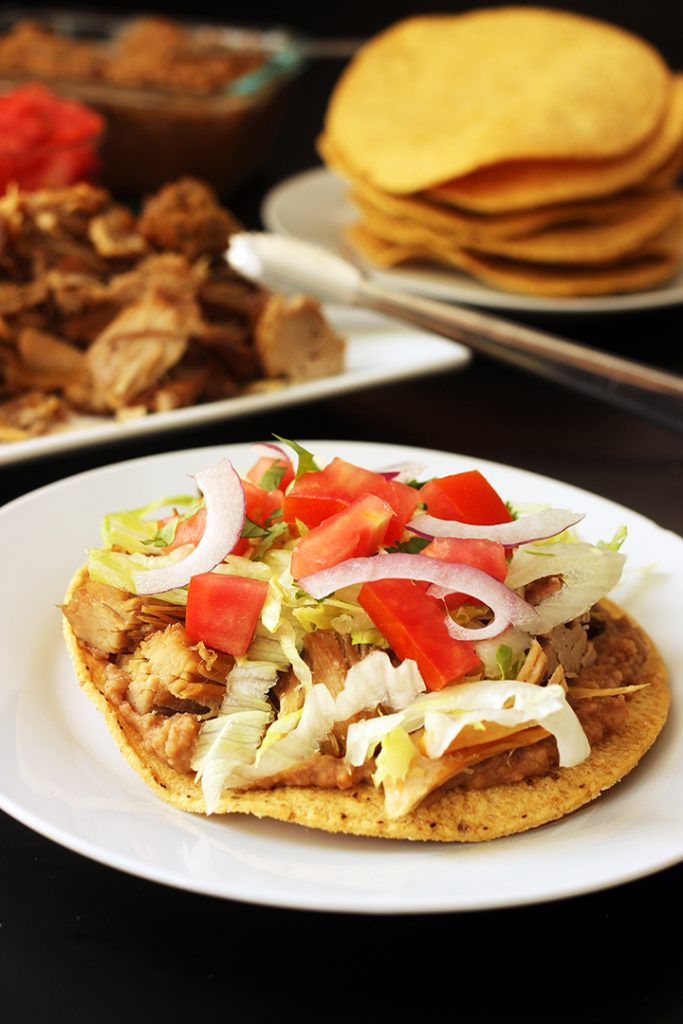 carnitas tostada on plate with other ingredients on table