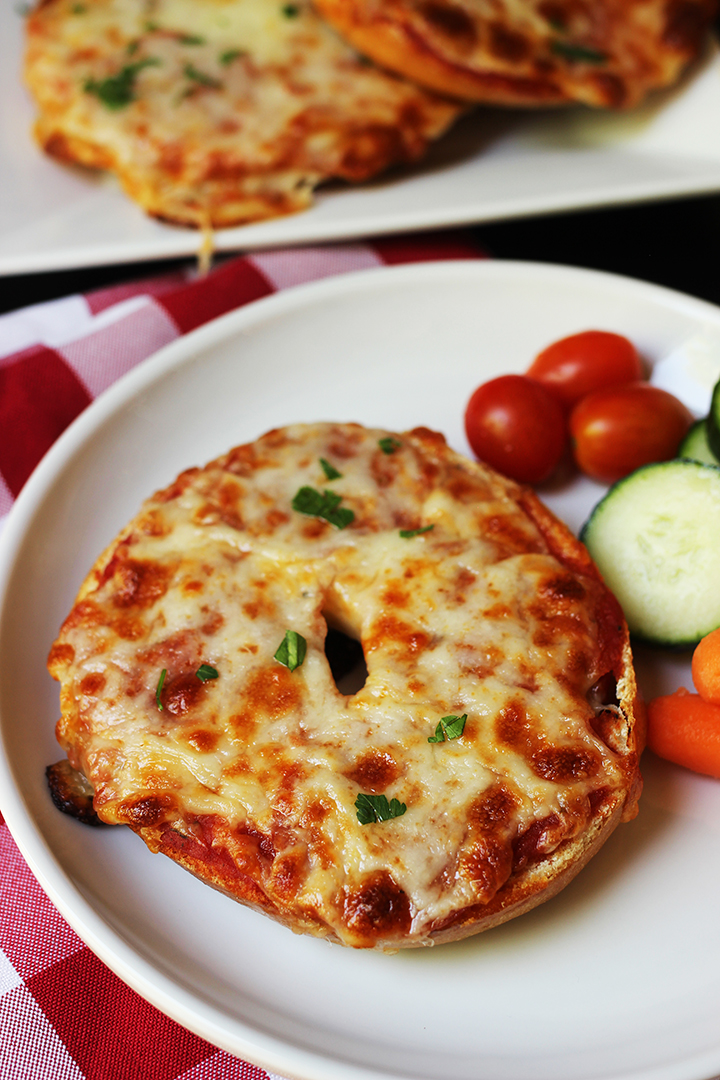 pizza bagel on plate with veggies