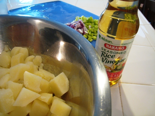 A bowl of cooked potatoes on a counter, with rice vinegar