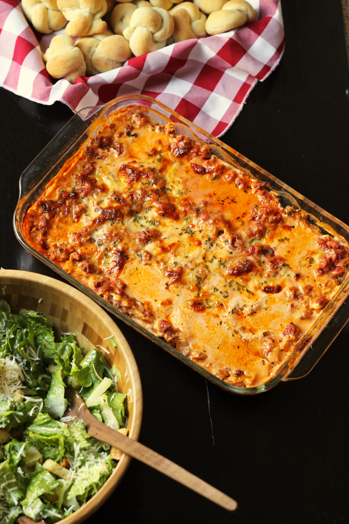 pan of lasagna with salad and bread knots