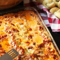 pan of lasagna with salad and rolls