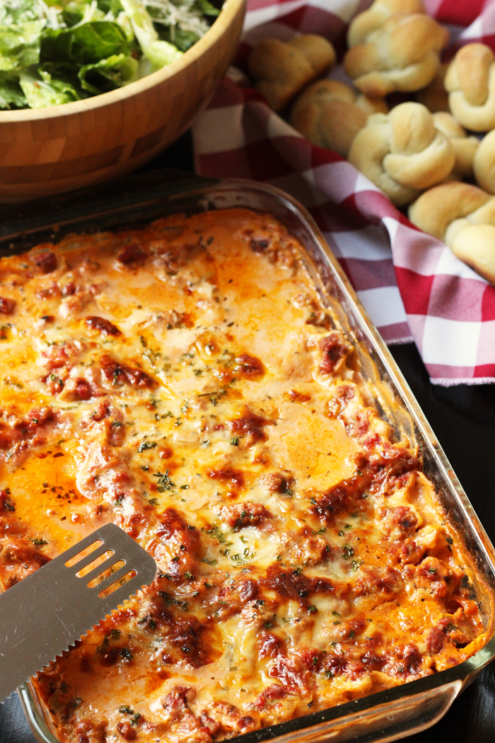 pan of lasagna with salad and rolls