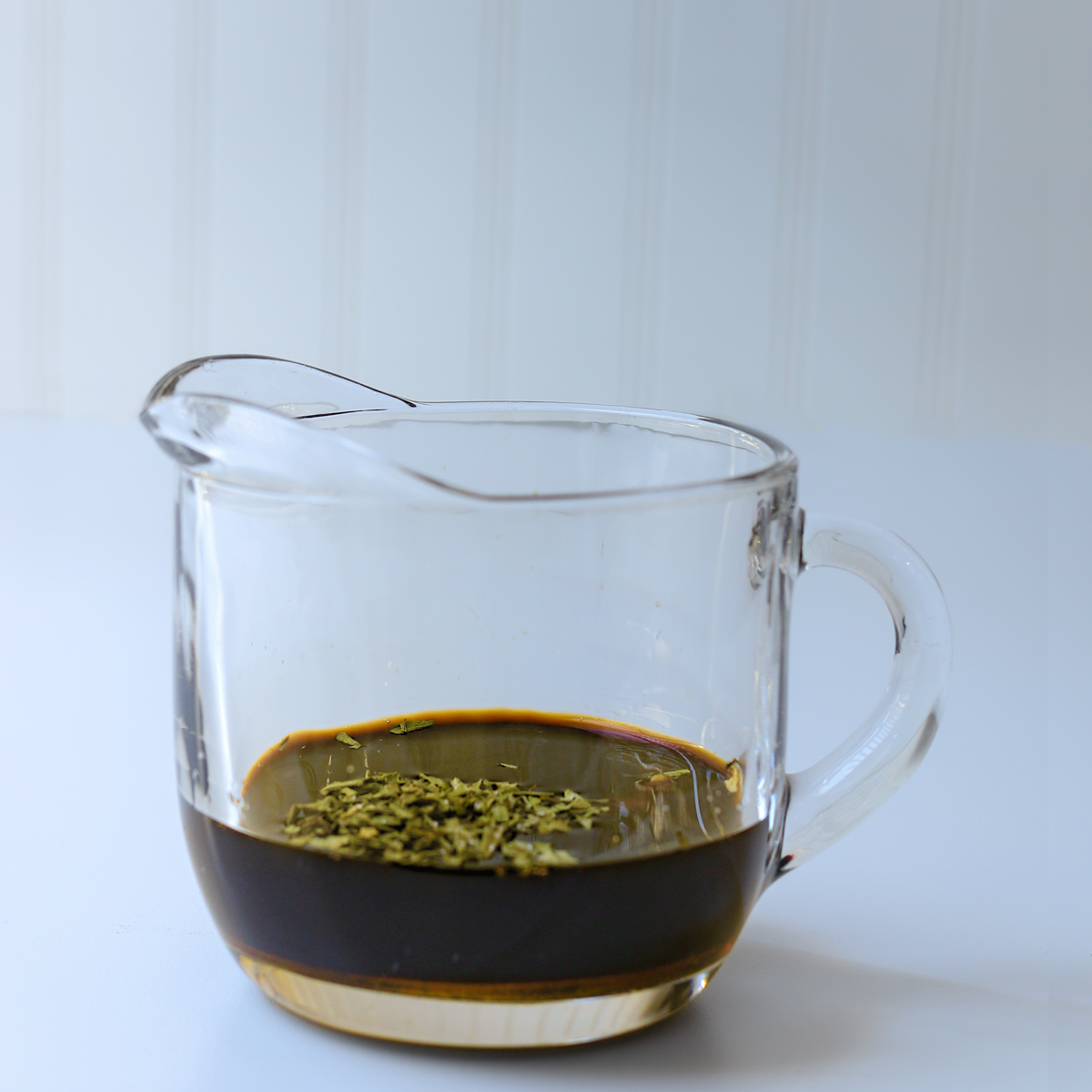 vinegar, mustard, maple, tarragon, and spices in small glass pitcher.