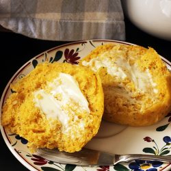 buttered pumpkin roll with butter knife on small flowered plate