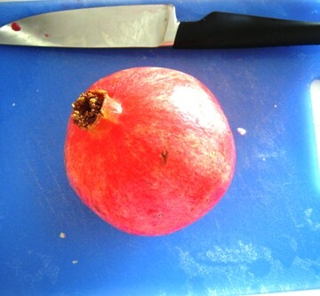 Pomegranate and knife on cutting board