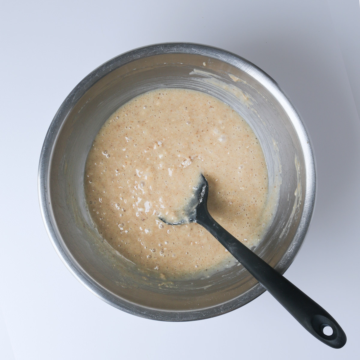 the coffee cake batter prepared in a mixing bowl with a black rubber spatula.