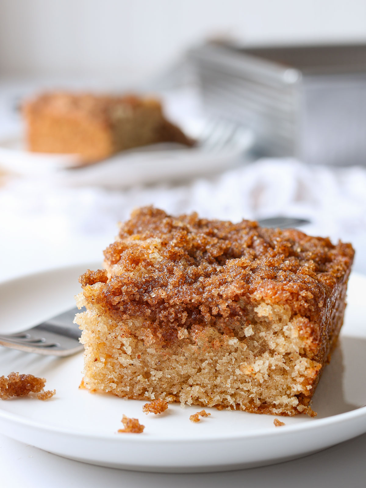 square of coffee cake on a plate with a fork and crumbs.