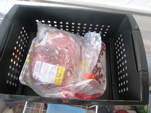 A plastic container filled with food, in Chest Freezer