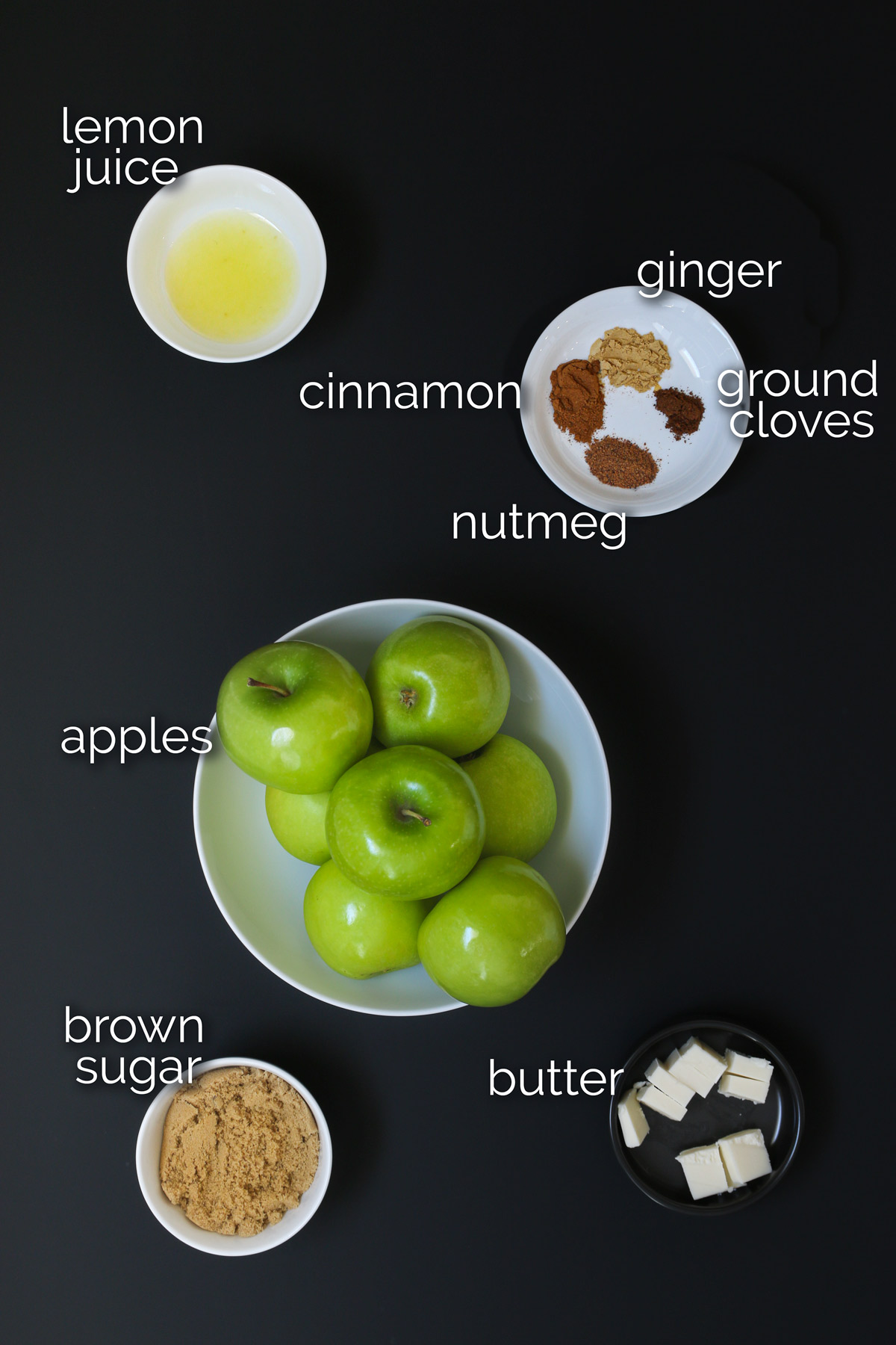 ingredients for apple compote laid out on a black table.