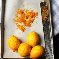 lemons on tray with zester and pile of zest.