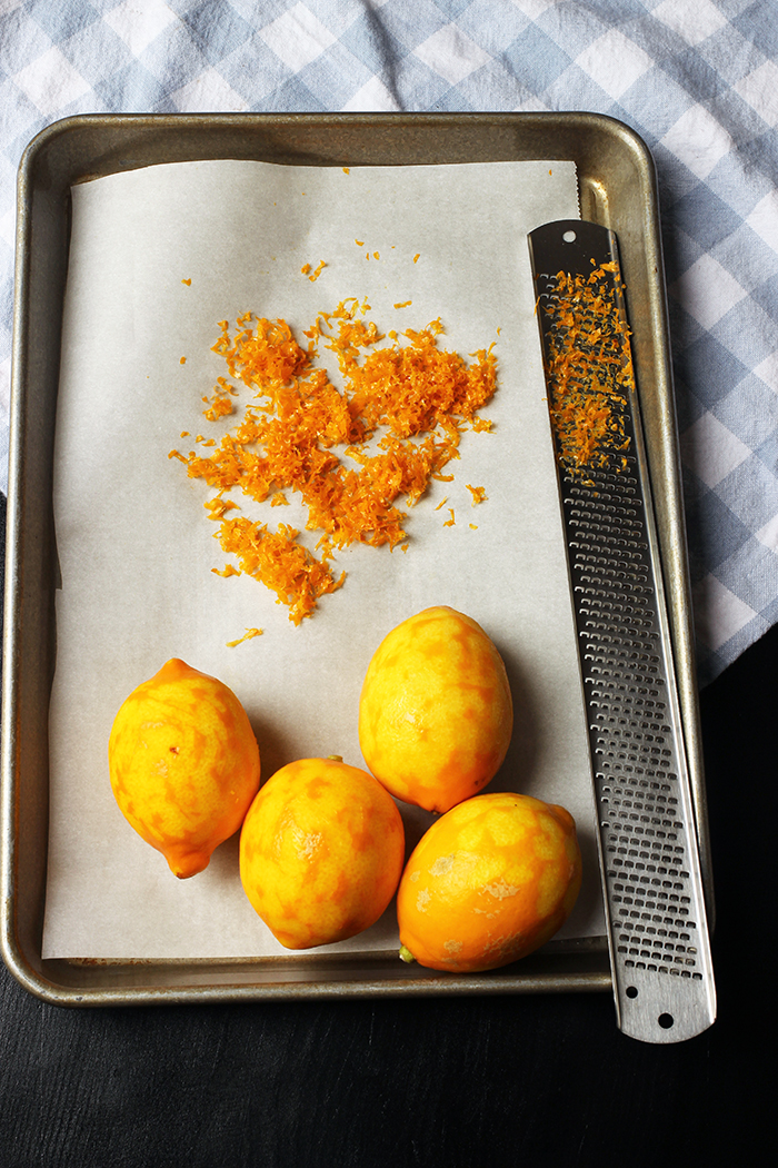 lemons on tray with zester and pile of zest.