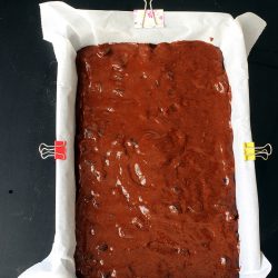 brownie batter in lined pan before clips are removed