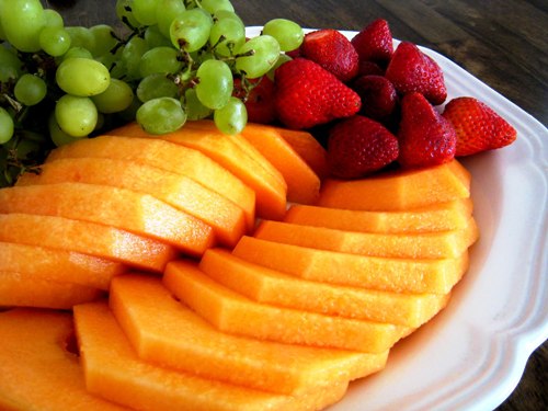A platter of melon slices, berries, and grapes