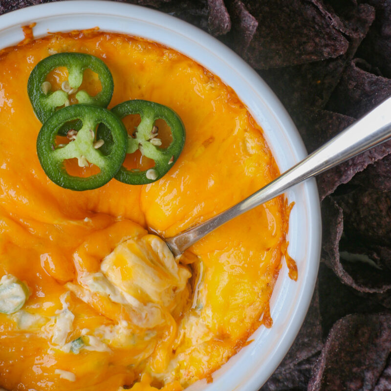 overhead shot of jalapeno cream cheese dip with sliced jalapeños on top and a spoon twirled in the cheese.