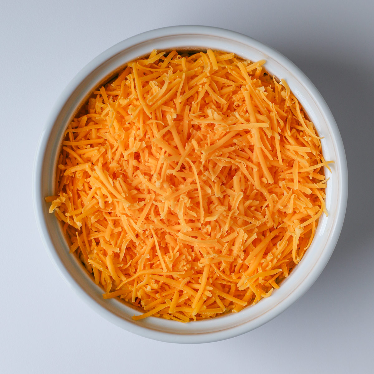 shredded cheese atop the cream cheese mixture in the white baking dish.