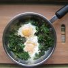 Eggs and Spinach in a skillet on a board