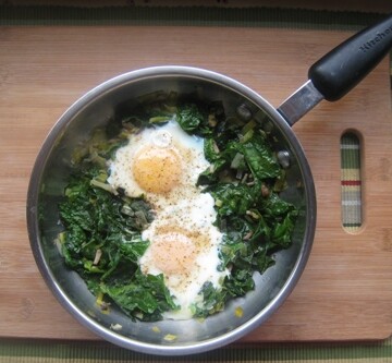 Eggs and Spinach in a skillet on a board