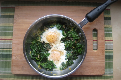 Eggs and Spinach in a skillet on a board