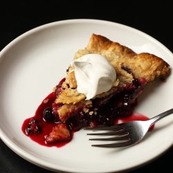 slice of berry pie on plate with whipped topping