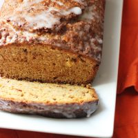 A Slice of carrot bread next to loaf on plate