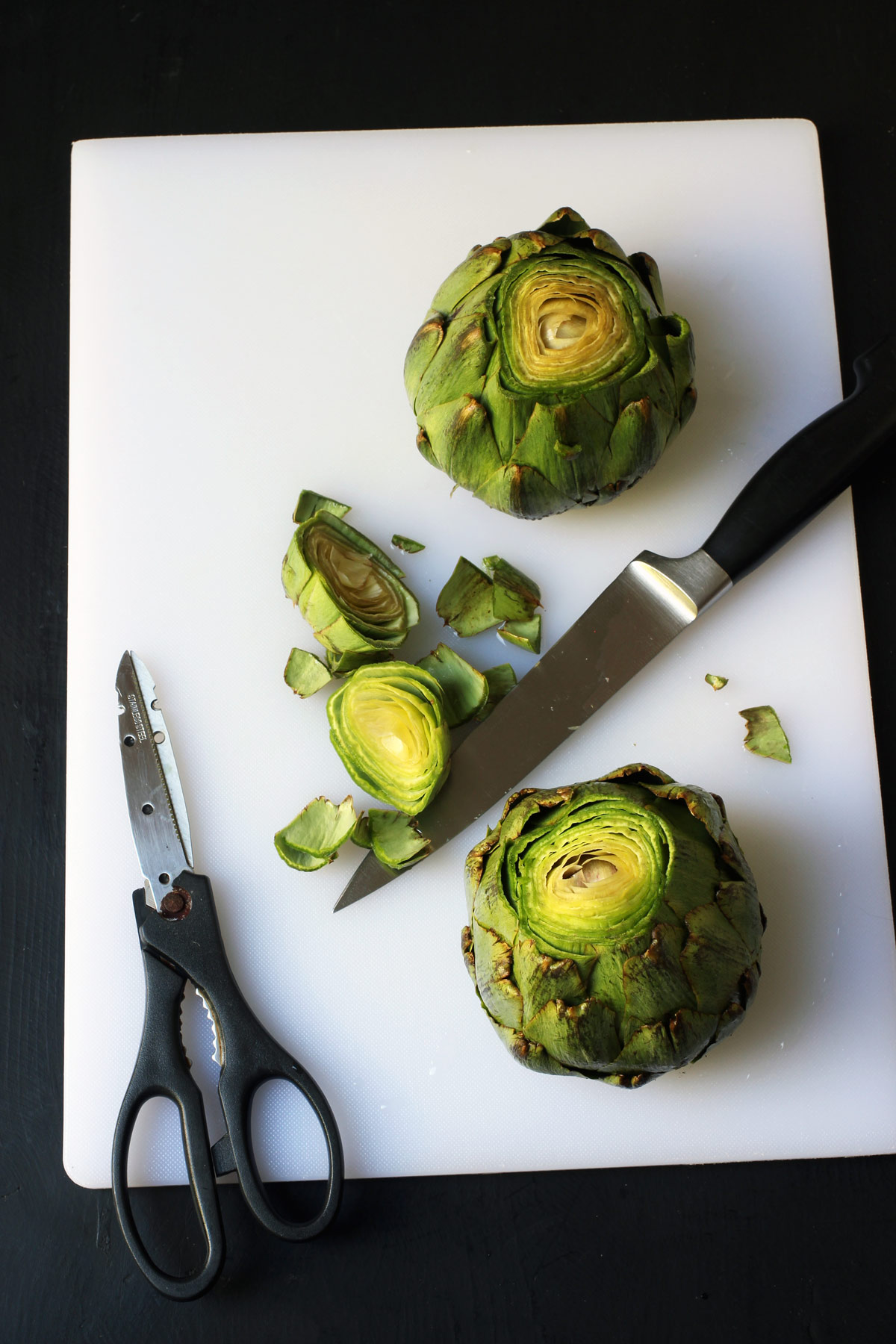 artichokes sitting upright on cutting board