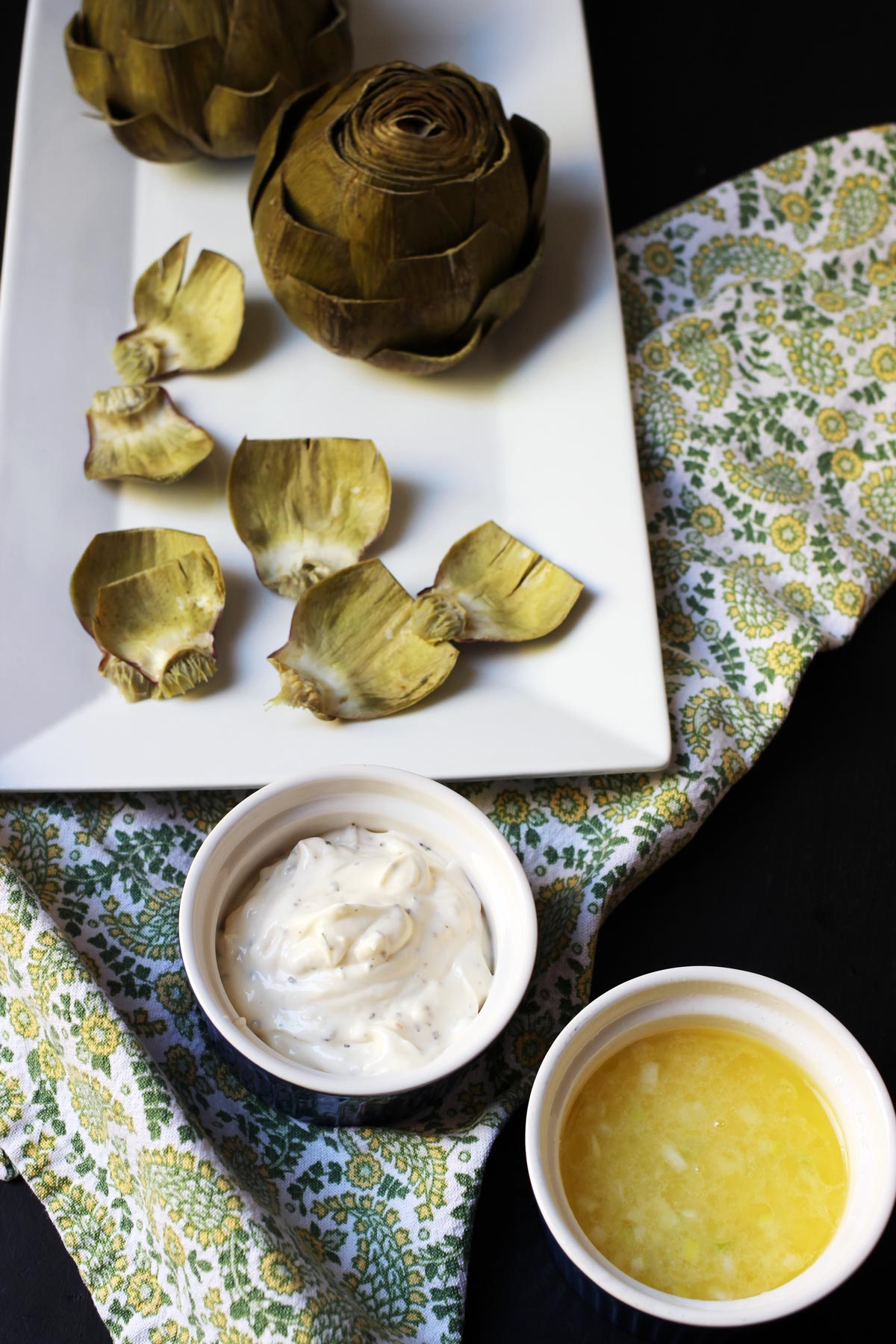 ramekins of sauces next to platters of artichokes