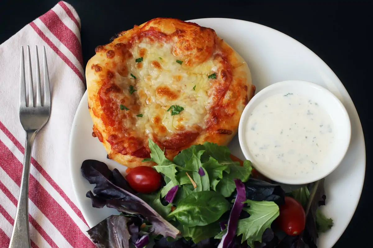 dinner plate with pizza, salad, and ranch dressing