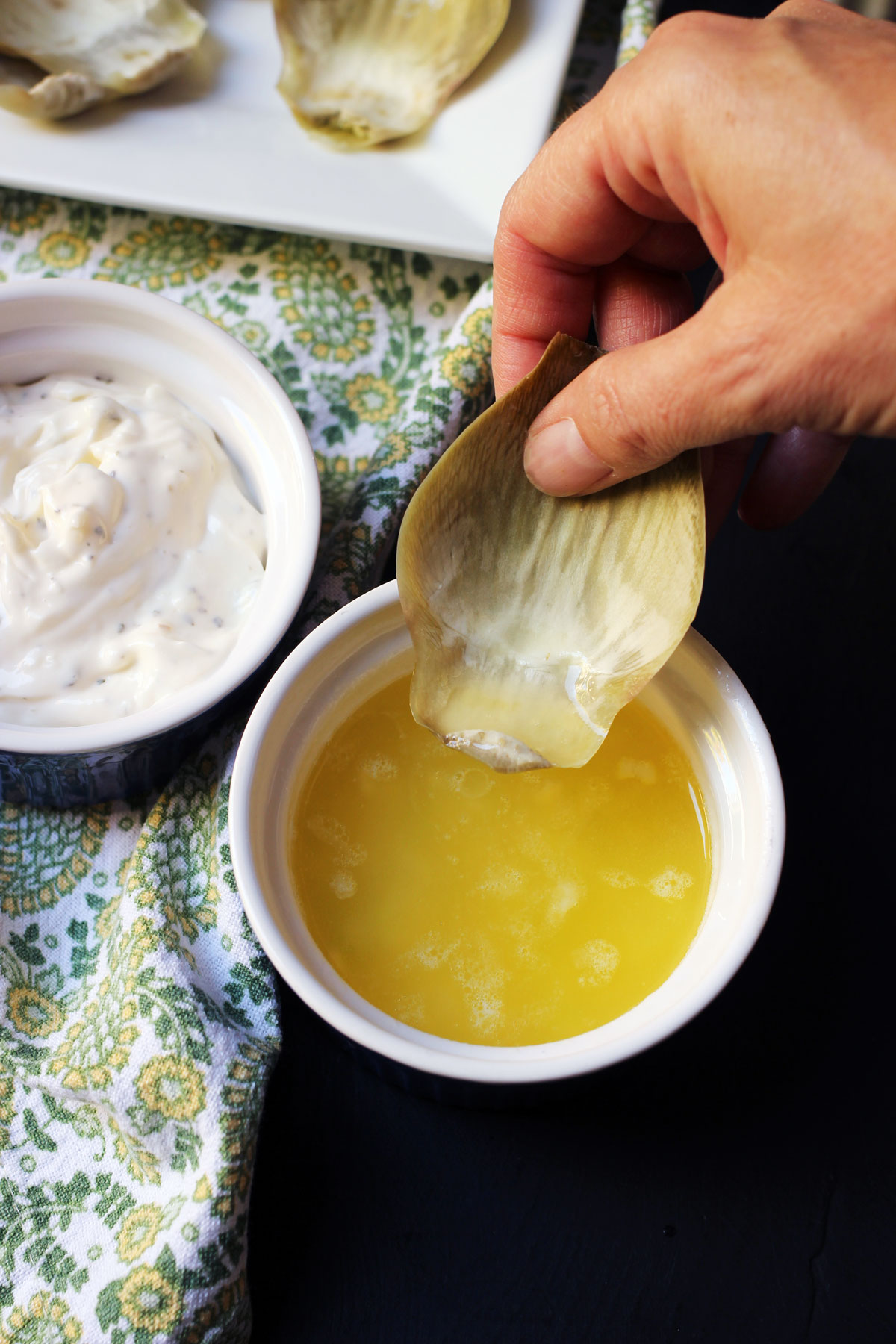 dipping artichoke leaf into butter sauce