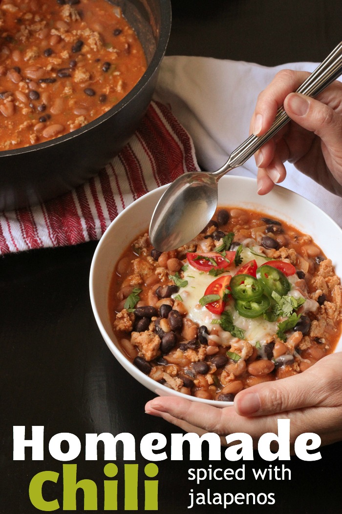 woman's hands holding bowl of chili with toppings