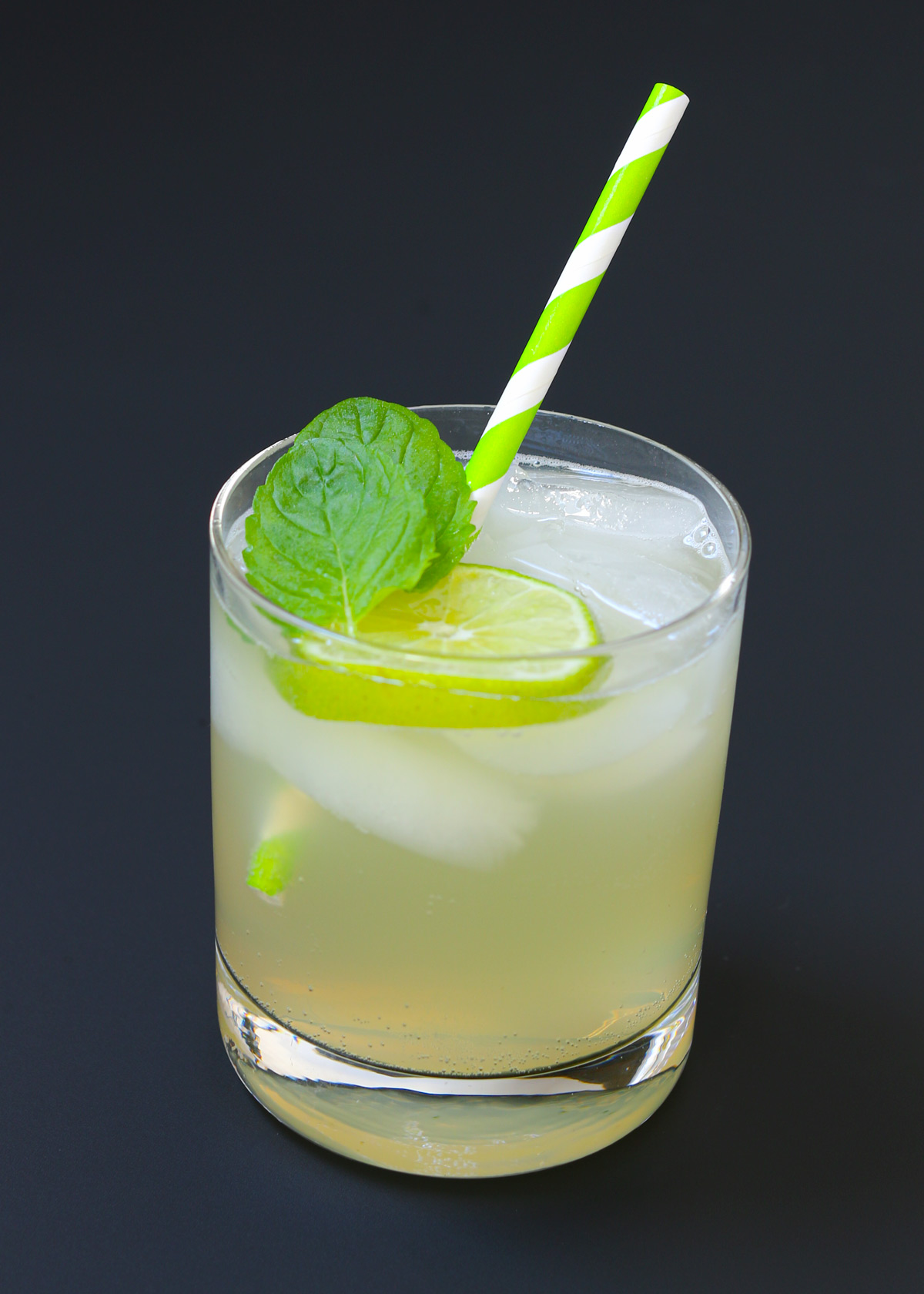 a green paper straw and garnishes are added to the mojito mocktail.