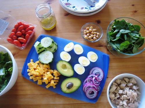 dishes of salad bar ingredients on wooden table