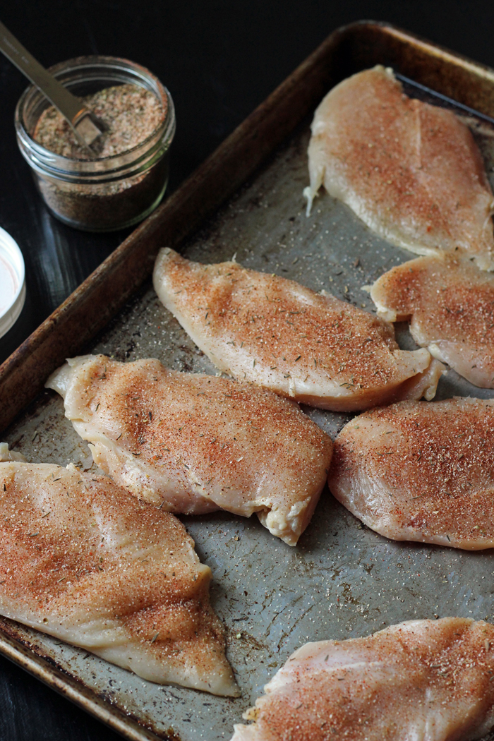 raw seasoned chicken breasts on a baking sheet