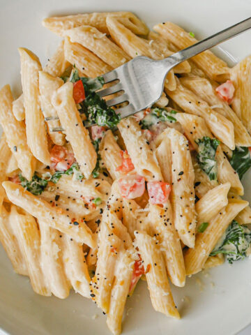 cream cheese pasta in white bowl with a fork.