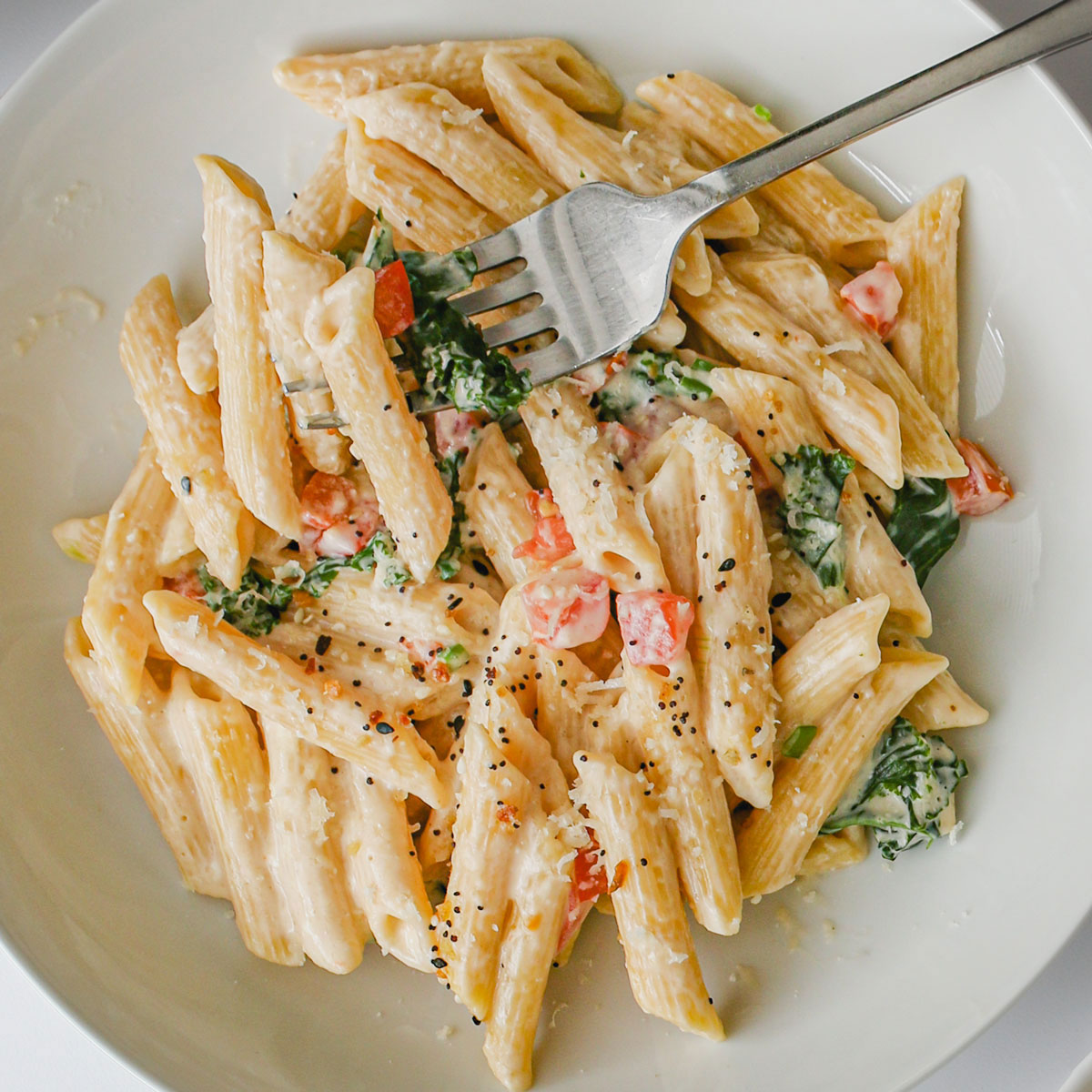 cream cheese pasta in white bowl with a fork.