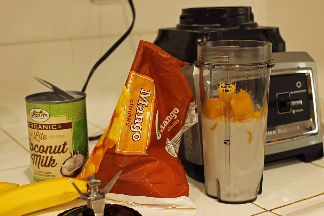 smoothie ingredients on counter, blender, and single serve cup