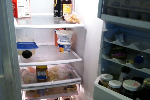 An almost empty refrigerator with the door open