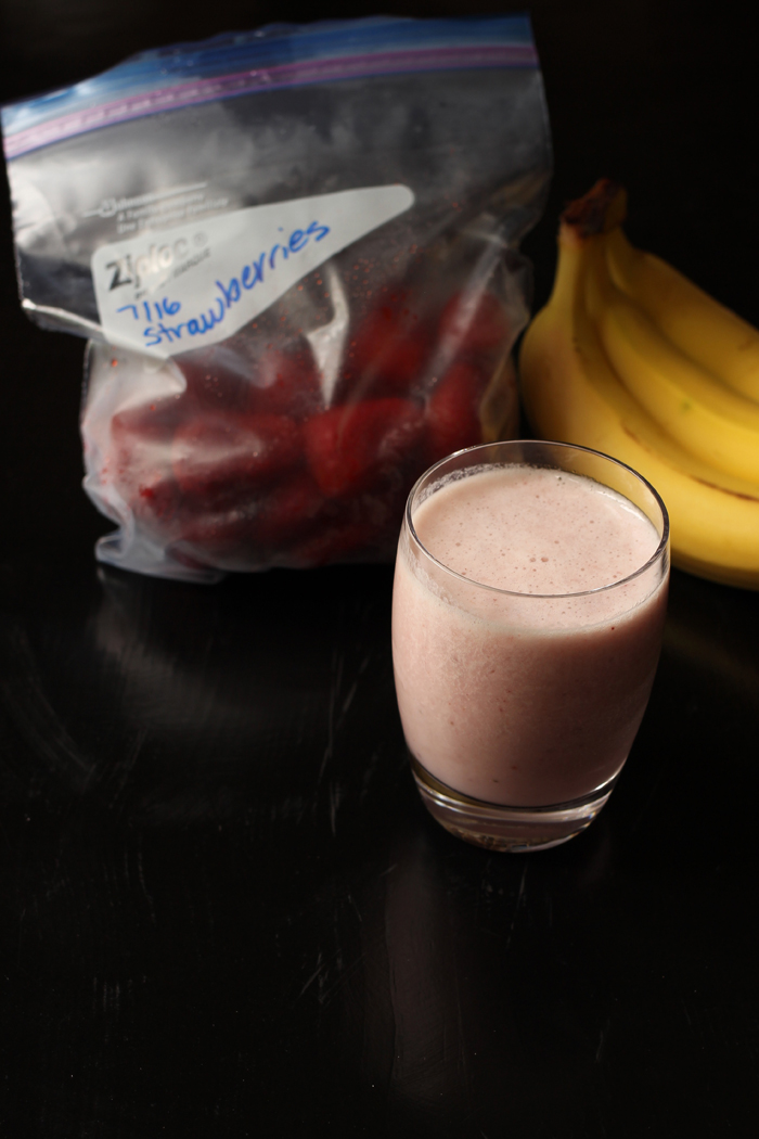 red banana smoothie with strawberries and bunch of bananas