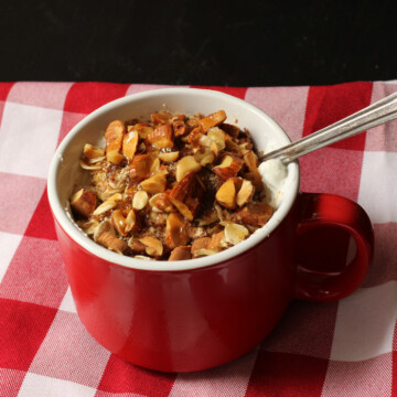 red mug of yogurt oats and nuts on gingham napkin