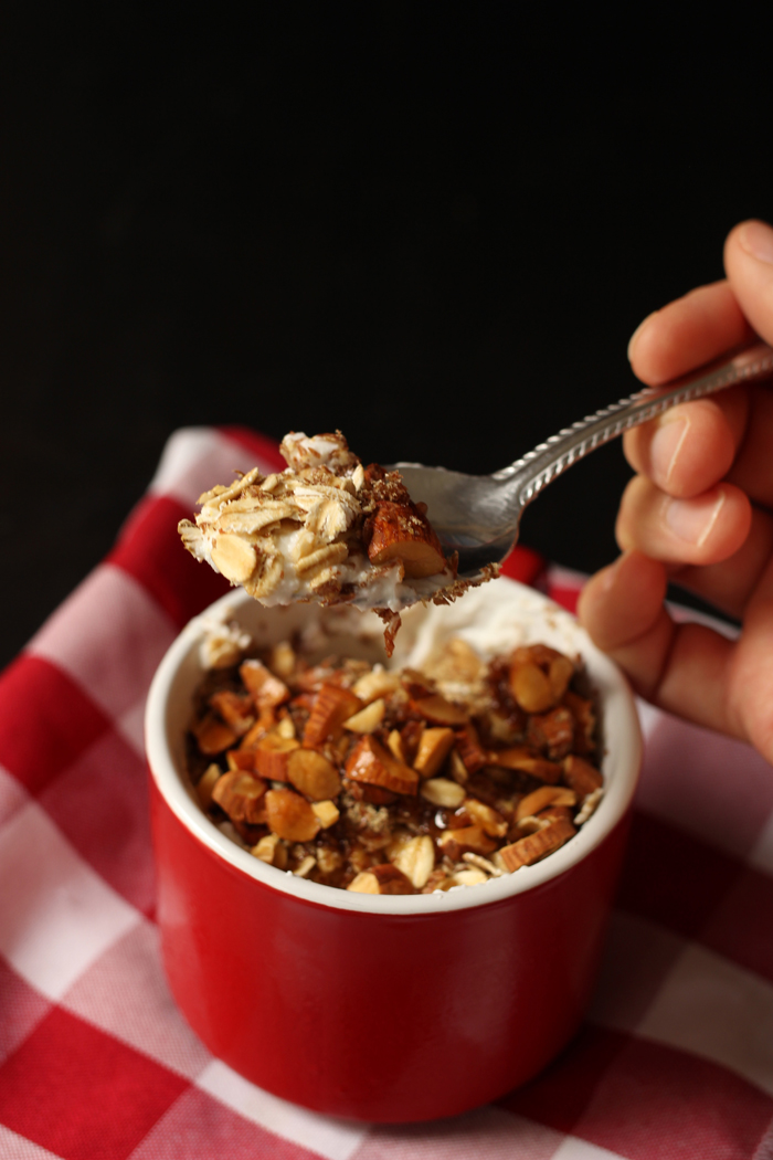 Someone holding a spoonful of yogurt and oats in a cup