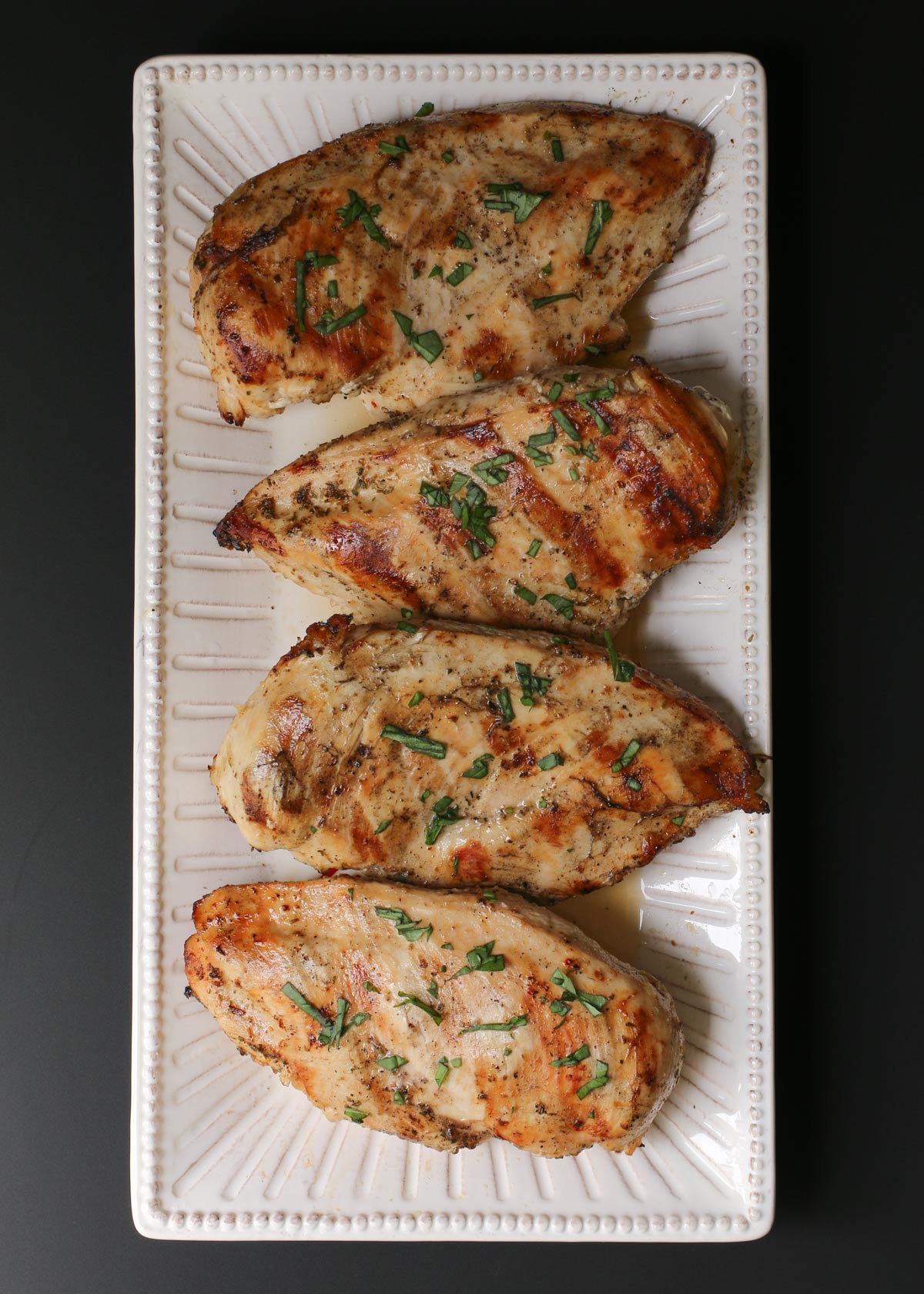 white platter of grilled marinated chicken.