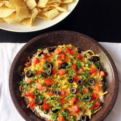 seven layer dip on white cloth with bowl of chips
